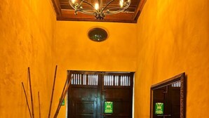 A hallway with wooden flooring, a chandelier, a large mirror, and a door with a sign. - w* |Marvelous 3BR House with pool in Cartagena (Cartagena de Indias)