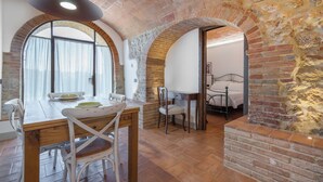 Un comedor con una mesa y sillas de madera, una pared de ladrillo y una ventana con cortinas.