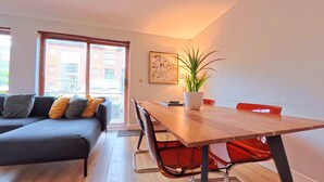 A modern living room with a sofa, a dining table, and a potted plant. - The Eastside Escape! Stunning 2 Bed Walk Anywhere (Belfast)