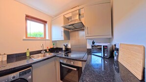 A modern kitchen with a built-in dishwasher, a stove, a microwave, and a toaster. - The Eastside Escape! Stunning 2 Bed Walk Anywhere (Belfast)