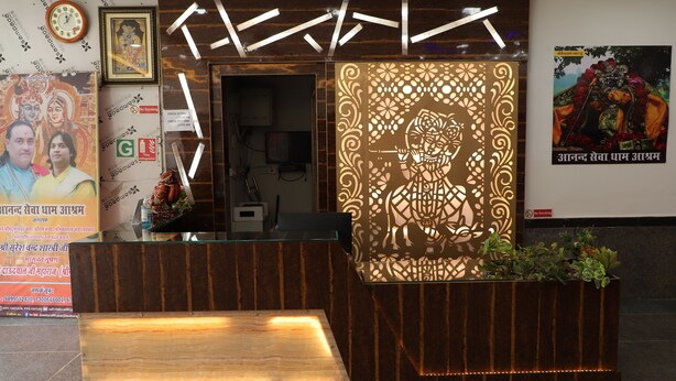 Un espace d’accueil comprenant un comptoir de réception en bois, un panneau décoratif représentant une figure divine et une affiche représentant également une figure divine.