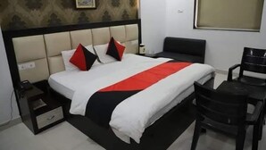 Une chambre d’hôtel avec un lit, une table de chevet, une chaise et une fenêtre.