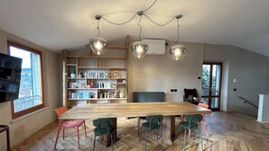 A spacious room with a large wooden dining table, multiple chairs, a bookshelf, and a radiator. - Garibaldi 14 Suite (Chianciano Terme)