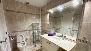 Un baño con inodoro, lavamanos, espejo y cabina de ducha.