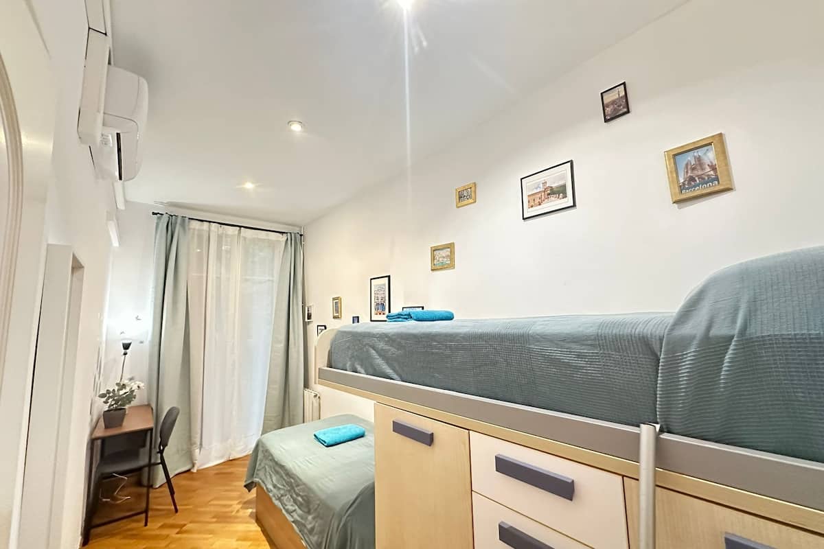 A compact bedroom with a bunk bed, a desk, and a chair.