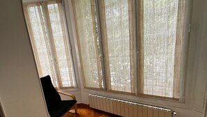 Una habitación con suelo de madera, una silla negra y un radiador.