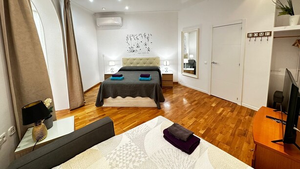 Un dormitorio moderno con cama, mesitas de noche, un espejo, un armario y un televisor.