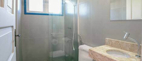 A modern bathroom with a glass-enclosed shower, a white toilet, and a marble sink.