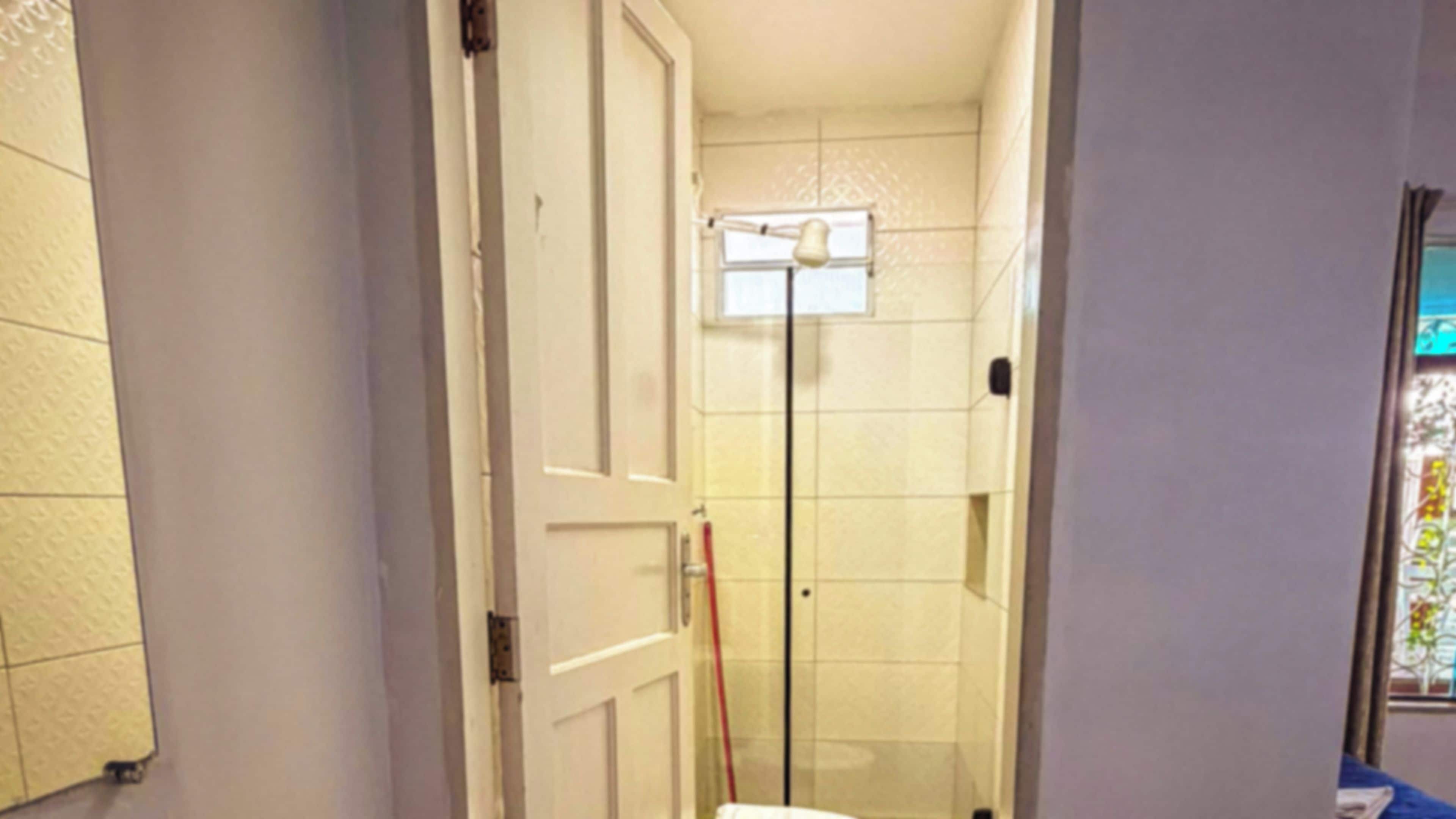 A narrow hallway with a glass door leading to a shower area.
