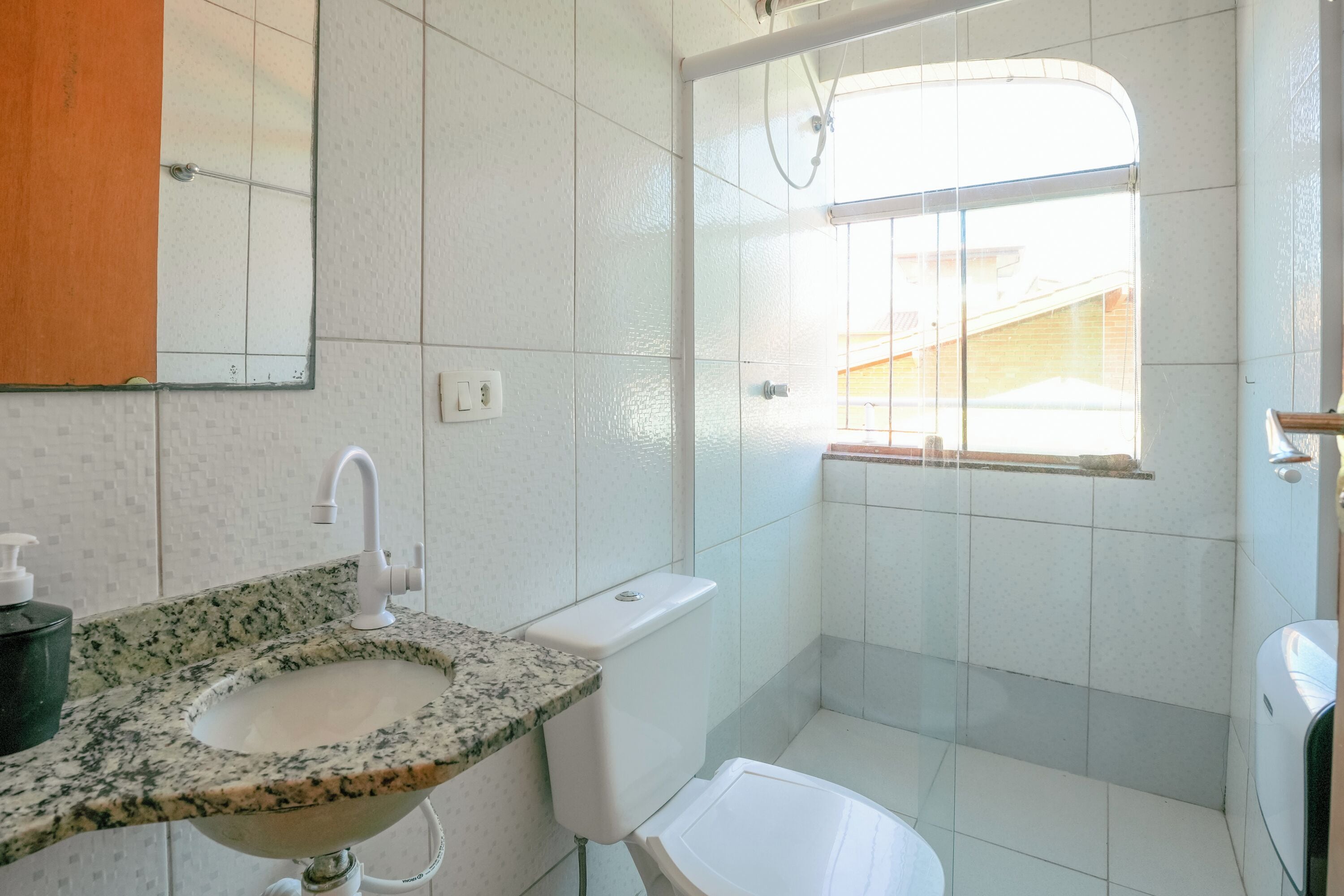 Une salle de bain avec un lavabo, des toilettes et une fenêtre.