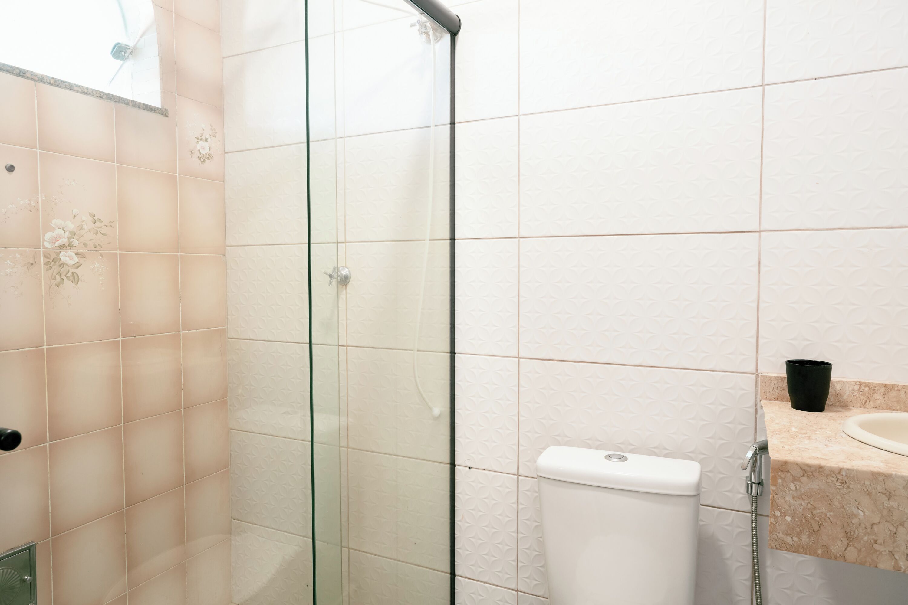 A bathroom with a glass shower enclosure, a toilet, and a sink with a marble countertop.