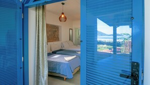 Een slaapkamer met twee bedden en uitzicht op de omgeving, met een blauwe deur.