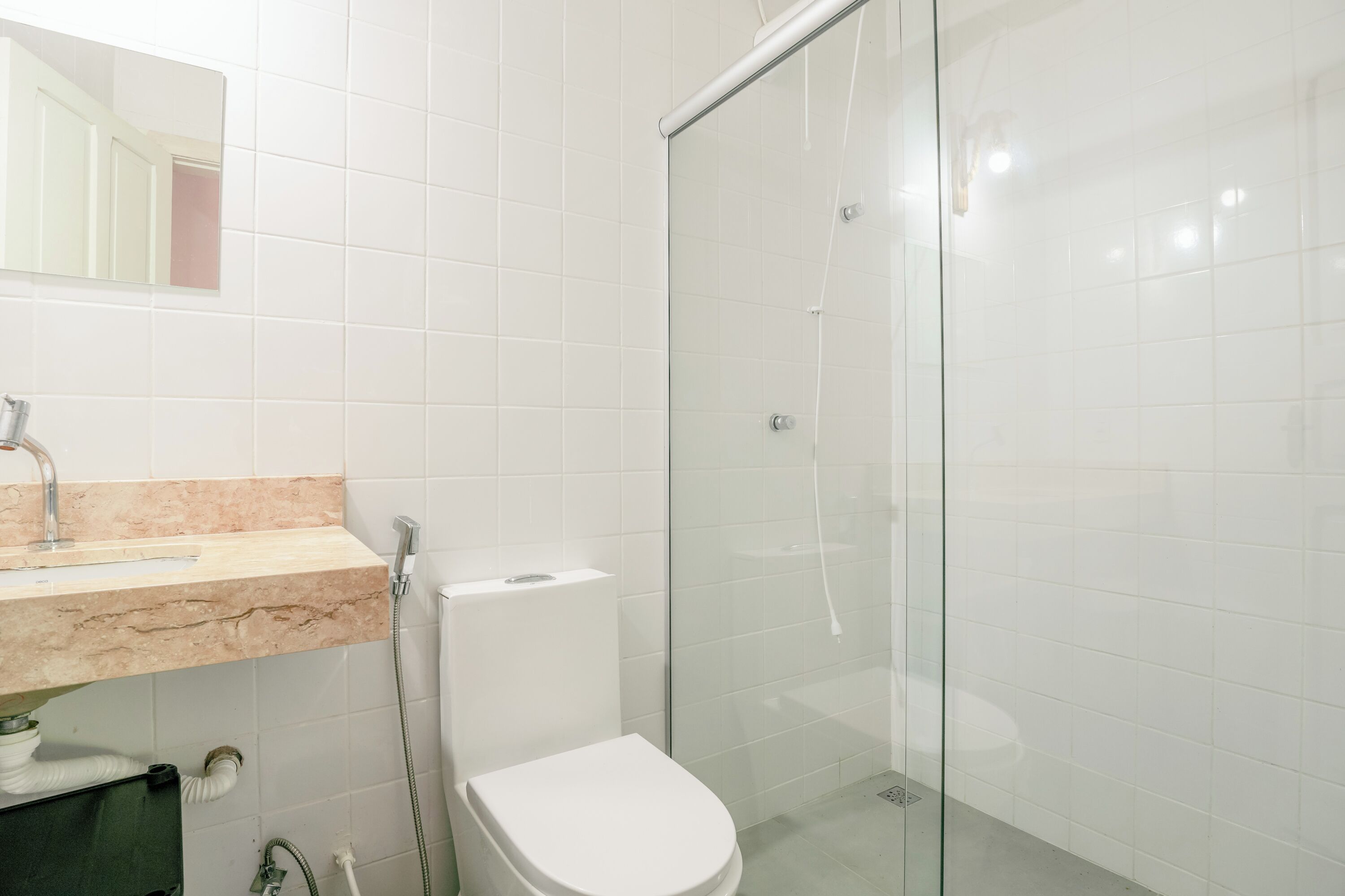 Un baño con lavamanos de mármol, inodoro y cabina de ducha de vidrio.