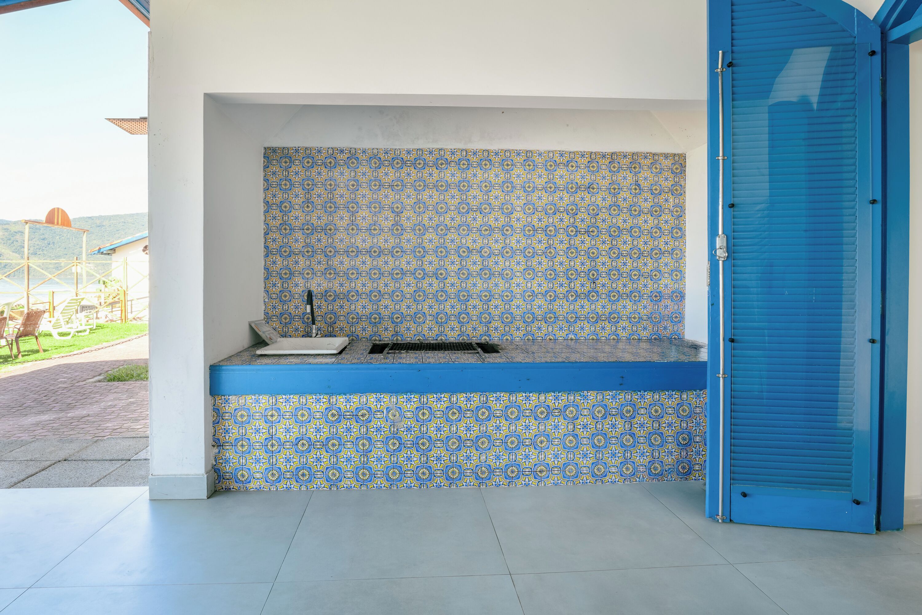 An outdoor kitchen area with patterned tiles and a blue door.