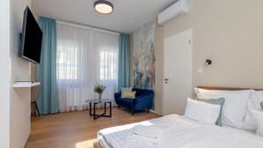 Una habitación de hotel con cama, televisión, escritorio, silla y un cuadro en la pared.