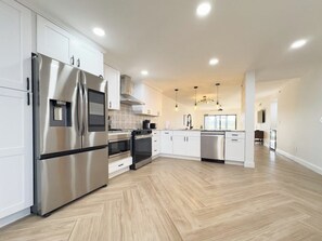 A modern kitchen with stainless steel appliances, white cabinetry, and a herringbone wood floor. - Golfer's dream!  Beautiful Condo at Kelly Greens Golf Club! (Fort Myers)