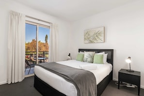 A hotel room with a bed, a nightstand, a lamp, a window with curtains, and a view of the outdoors. - Park Views on Hurtle: CBD, balcony, tennis court (Adelaide)