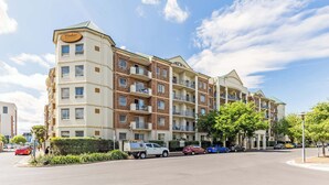 Ett hotell med flera våningar, balkonger, en parkeringsplats och en klar himmel.