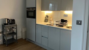 A compact kitchen with a built-in oven, a small countertop, and a sink. - 2br-modern-fullkitchen-25mincentrallondon-parking (Rickmansworth)