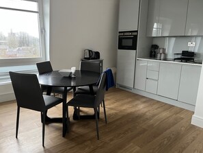 Een moderne keuken met een ronde eettafel, stoelen en een ingebouwde oven.