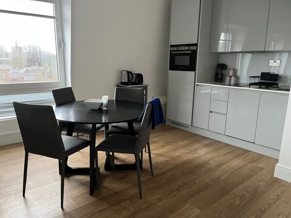 Et moderne køkken med et rundt spisebord, stole og en indbygget ovn.