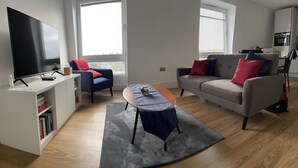 A modern living room with a flat-screen TV, a sofa, a chair, and a coffee table. - 2br-modern-fullkitchen-25mincentrallondon-parking (Rickmansworth)
