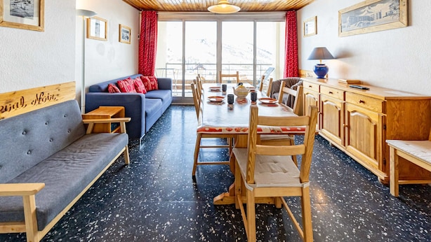 A cozy room with a wooden ceiling, a sofa, a dining table with chairs, and a kitchen area. - Spacious 8 pers. apartment at the foot of the slopes (Saint-François-Longchamp)