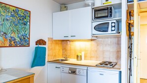 A compact kitchen with white cabinets, a microwave, a dishwasher, and a sink.