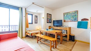 A cozy room with a bed, a wooden table, a TV, and a painting on the wall.