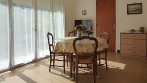 A dining area with a table set for four, chairs, a television, and a wooden cabinet. - 2-bedroom apartment near beach, private garden, pets allowed (Argelès-sur-Mer)