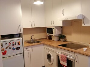 Compact kitchen with refrigerator, microwave, oven, and sink.