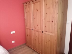 A spacious room features a large wardrobe with two doors and a central panel, complete with handles and a lock.