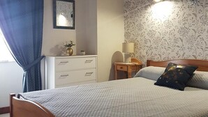 A neatly arranged bedroom with a bed, a dresser, a nightstand, and a lamp.
