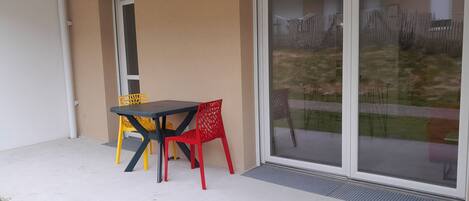 A patio with a table and chairs, a sliding glass door, and a small window.
