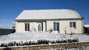 Una casa de un piso con tejado nevado y base de piedra.