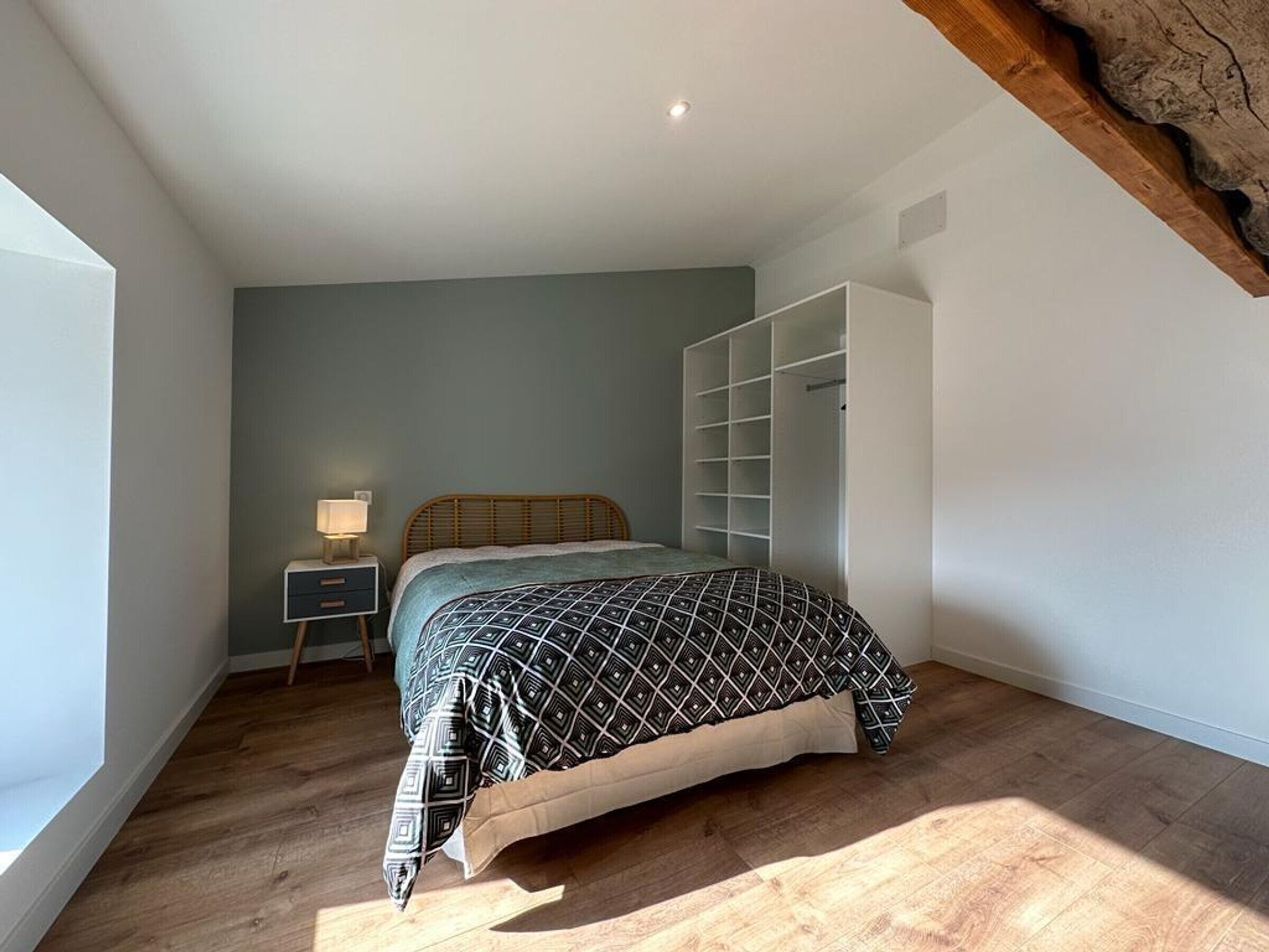 A bedroom with a bed, a nightstand, a wardrobe, and a window.