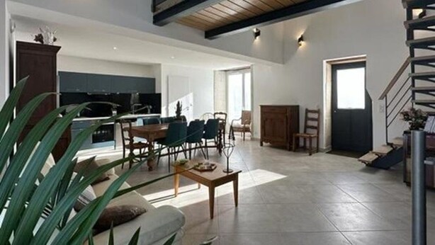 A spacious living area with a high ceiling, a staircase, and a kitchen in the background. - Cozy house with pool and garden in Brantôme (Brantôme en Périgord-Brantôme en Périgord)