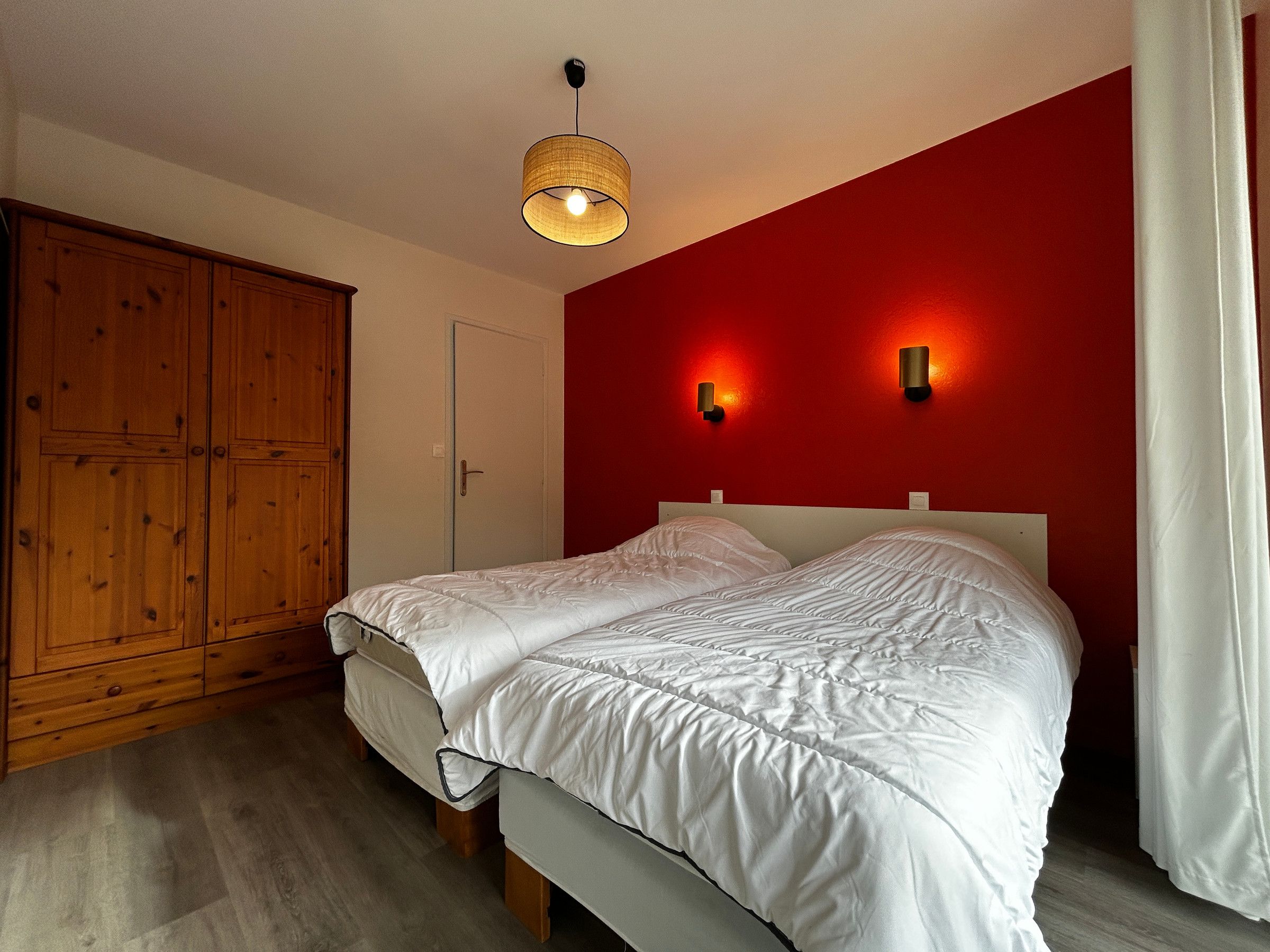 Ein Schlafzimmer mit einem Bett, einem Holzschrank und zwei Wandleuchten.