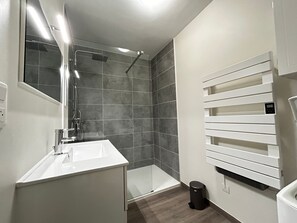 A modern bathroom with a shower, a sink, and a toilet. - Spacious refurbished apartment with balcony and garage, near city center (Évian-les-Bains)