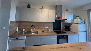 Une cuisine moderne avec des armoires blanches, une hotte noire et un four à micro-ondes posé sur le plan de travail.