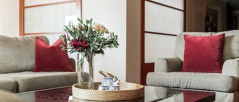 Una sala de estar con dos sofás, una mesita de centro y un florero con flores.