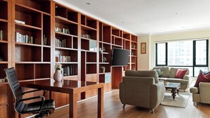 A spacious living area with a wooden bookshelf, a flat-screen TV, and a comfortable seating arrangement.