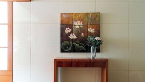 Una consola de madera con un jarrón de flores y un cuadro de flores en la pared.