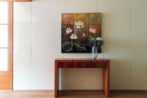 Una consola de madera con un jarrón de flores y un cuadro de flores en la pared.