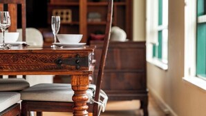Una mesa de comedor con sillas, una copa y un tazón.