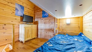 Habitación de cabaña de madera con una cama, un televisor y un armario de madera.