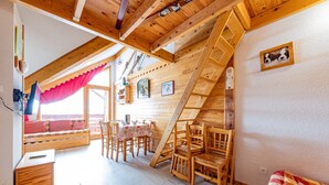 Una cabaña acogedora con habitación en el altillo, muebles de madera y zona de comedor.