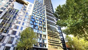 A modern high-rise building with multiple floors, large windows, and a mix of glass and metal facade.