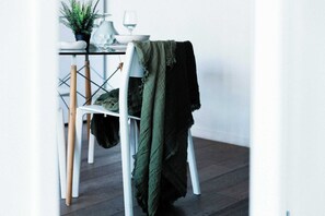A dining area with a white table, a potted plant, and a chair with a green blanket. - Pet-friendly Stylish 2BR Apt, Panoramic City Views (Melbourne)