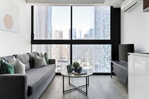 Un salon moderne avec un canapé gris, une table basse ronde et un meuble pour la télévision.
